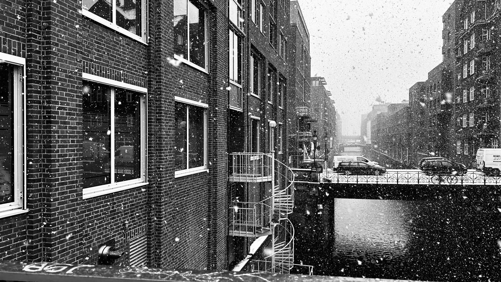 Persoon bij een groot raam in de winter waar koude lucht langs het glas naar beneden zakt